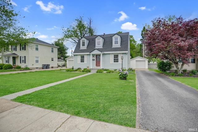 view of front of house featuring aphalt driveway, an outdoor structure, a detached garage, and a front yard