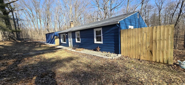 view of side of property featuring fence and a chimney