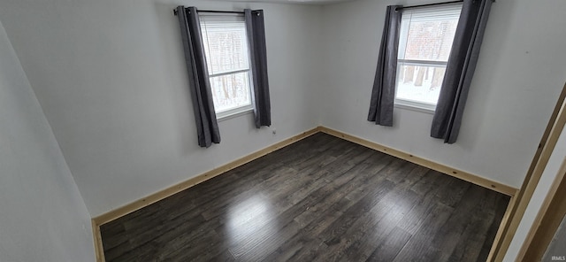 empty room with dark wood-type flooring and baseboards