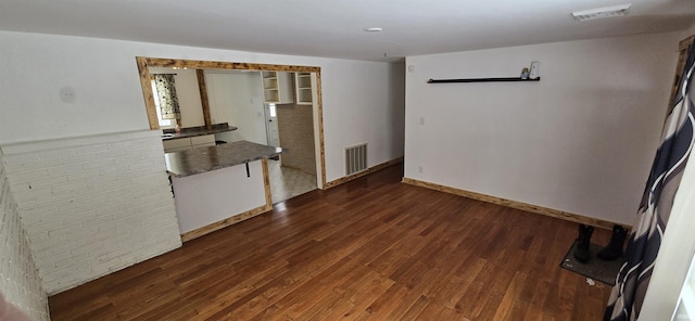 interior space with dark countertops, brick wall, visible vents, and dark wood-type flooring