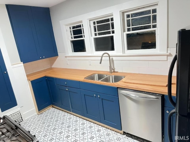 kitchen with blue cabinetry, stainless steel dishwasher, a sink, and freestanding refrigerator