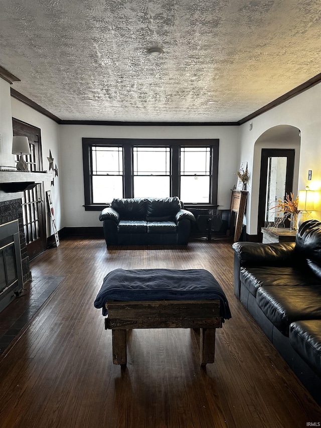 living area with hardwood / wood-style flooring, a fireplace, arched walkways, and a textured ceiling