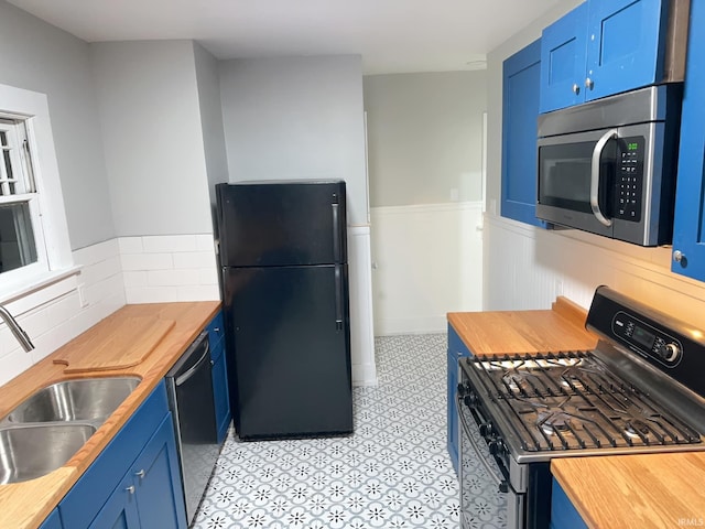 kitchen featuring butcher block countertops, a sink, blue cabinetry, and black appliances