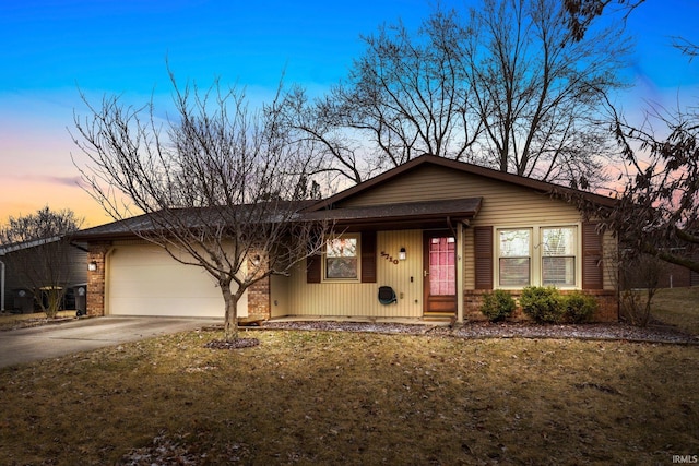 view of front facade featuring concrete driveway, brick siding, an attached garage, and a front yard