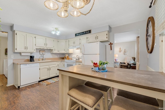 kitchen with dark wood-style floors, a sink, a textured ceiling, white appliances, and under cabinet range hood