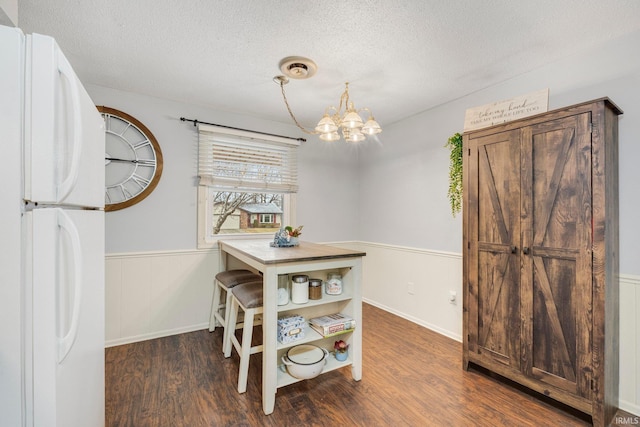 dining room with wainscoting, a notable chandelier, a textured ceiling, and wood finished floors