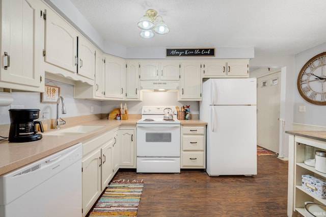 kitchen featuring white appliances, dark wood-style floors, under cabinet range hood, white cabinetry, and a sink