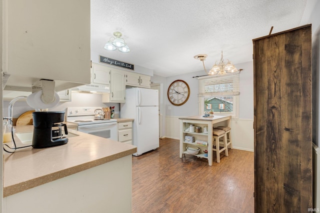 kitchen featuring white appliances, dark wood-style floors, light countertops, a textured ceiling, and under cabinet range hood