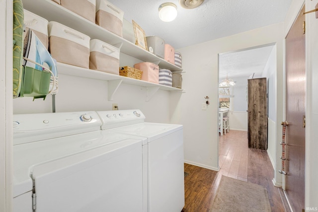 laundry area with a textured ceiling, laundry area, separate washer and dryer, wood finished floors, and baseboards