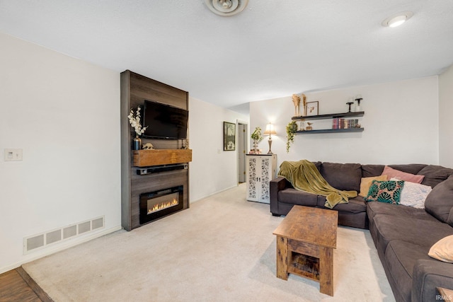 living room featuring a large fireplace, visible vents, and light colored carpet