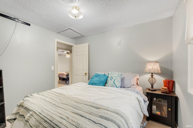 bedroom featuring a textured ceiling, carpet floors, and attic access