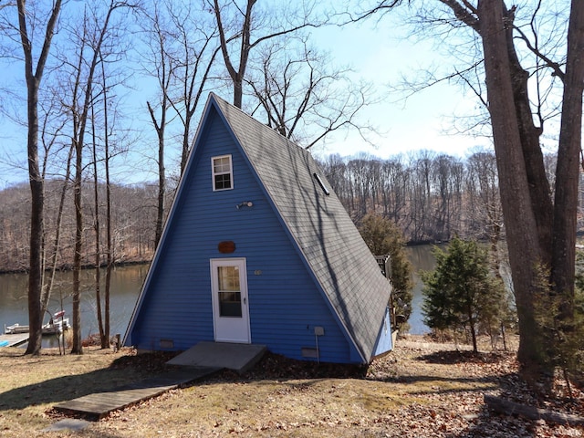 view of front of property with a forest view and roof with shingles