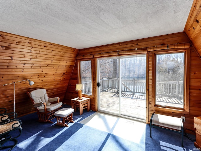 unfurnished room featuring lofted ceiling, carpet, wooden walls, and a textured ceiling