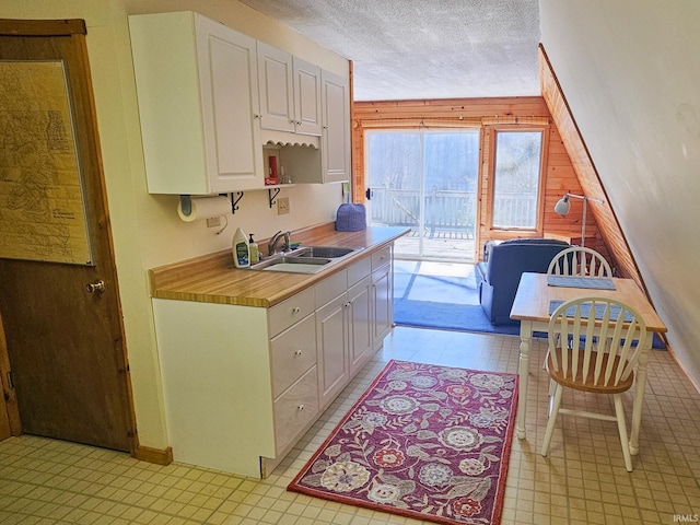 kitchen featuring light countertops, white cabinets, a sink, and a textured ceiling