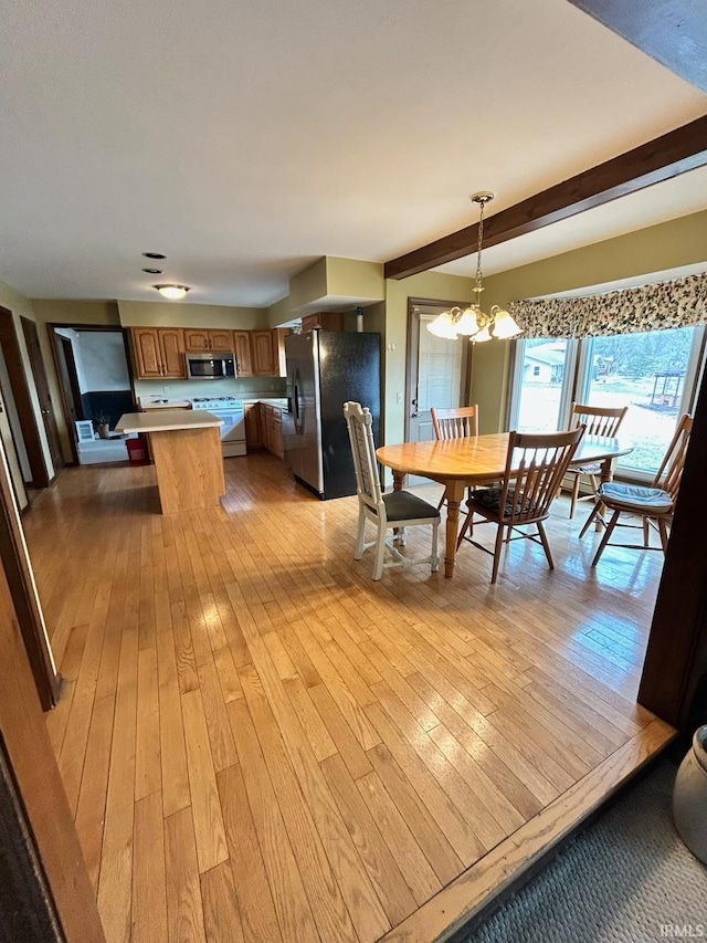 dining space with beam ceiling, light wood-style flooring, and an inviting chandelier