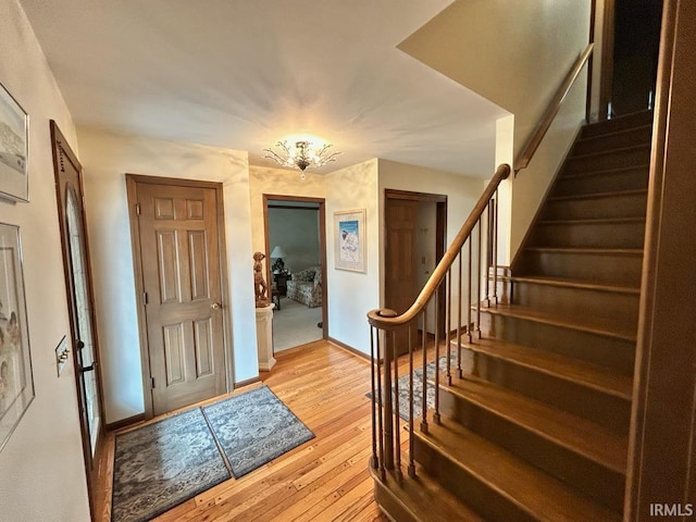 foyer with stairs, light wood finished floors, and baseboards