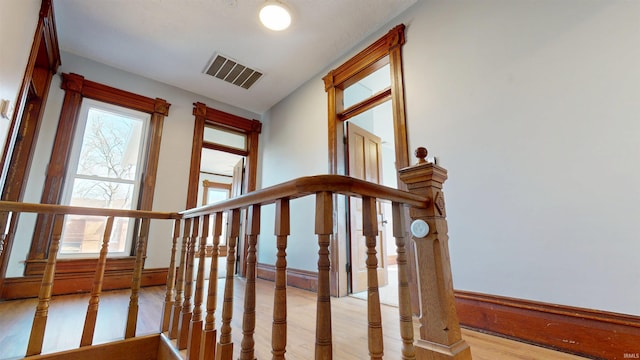 staircase featuring a wainscoted wall, visible vents, and wood finished floors