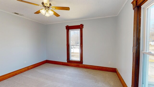 carpeted empty room with ornamental molding, visible vents, baseboards, and a ceiling fan