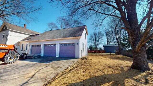 garage featuring concrete driveway and fence