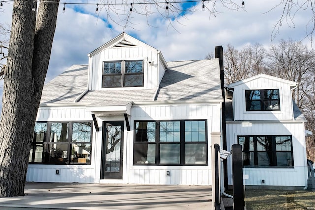 modern inspired farmhouse featuring a shingled roof, board and batten siding, and a chimney