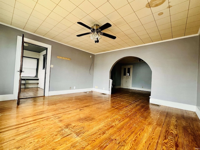 spare room with ornamental molding, arched walkways, visible vents, and wood finished floors