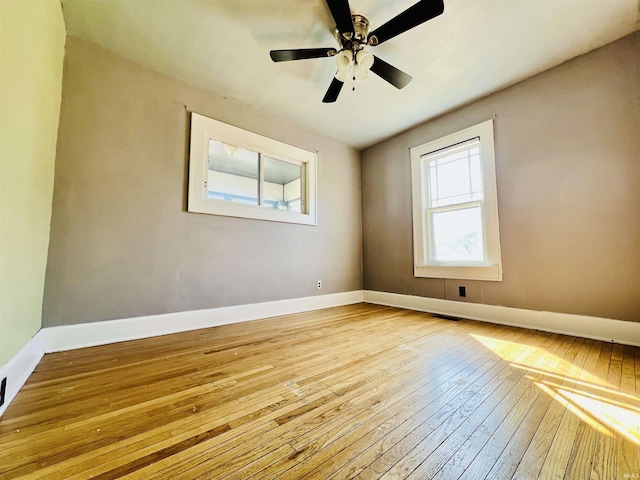 spare room featuring wood-type flooring, baseboards, and ceiling fan