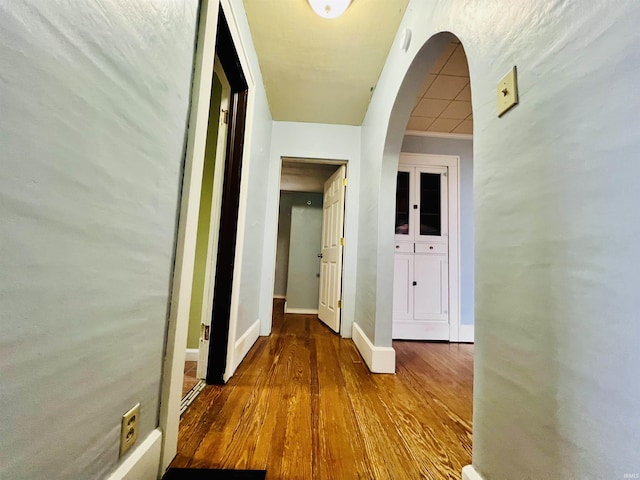 hall with baseboards and wood finished floors