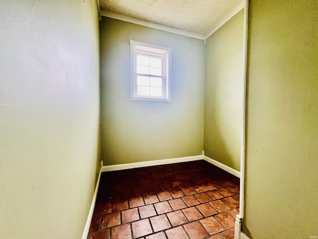 spare room with a textured ceiling and baseboards