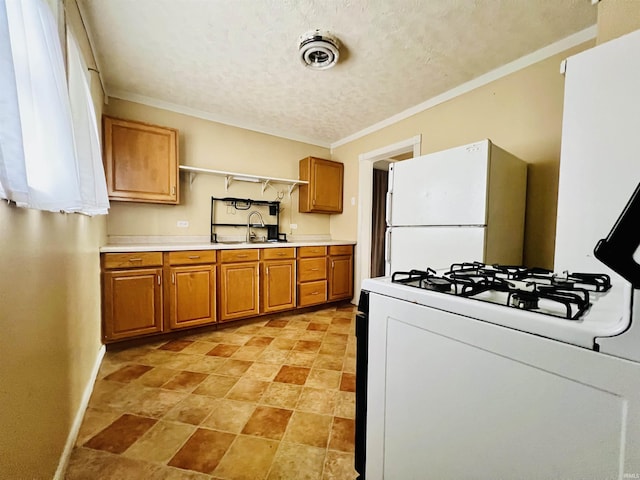 kitchen with white appliances, a sink, light countertops, brown cabinetry, and crown molding