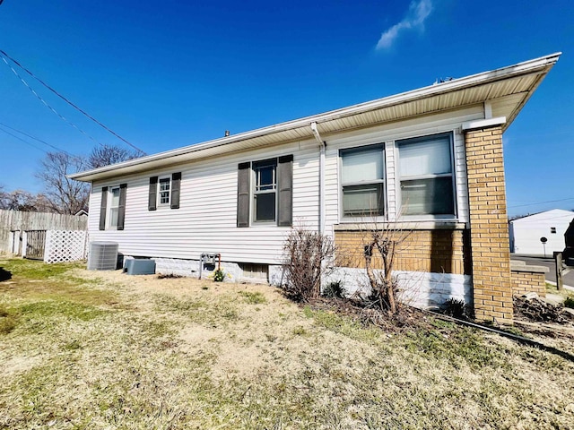 back of house with a yard, fence, central AC unit, and brick siding