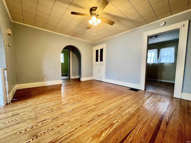 empty room with arched walkways, visible vents, and crown molding