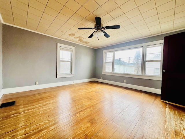 spare room with ornamental molding, wood-type flooring, visible vents, and baseboards