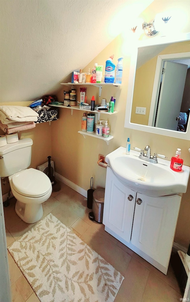 bathroom with toilet, vaulted ceiling, a textured ceiling, vanity, and tile patterned floors