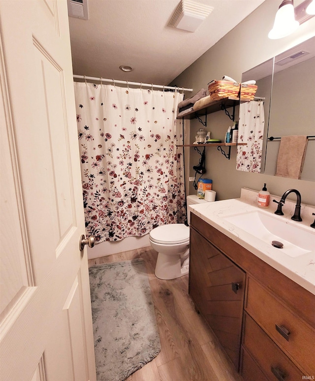 full bath with toilet, visible vents, wood finished floors, and vanity