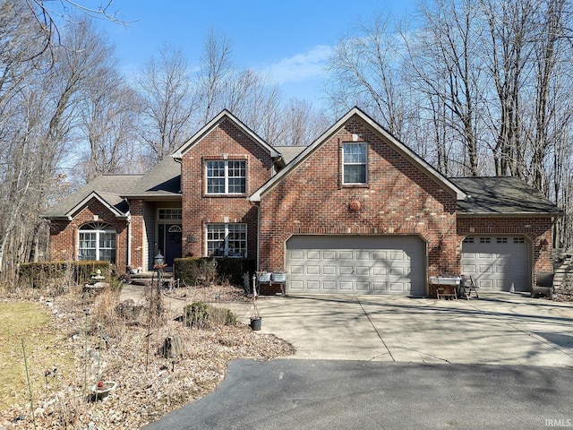 traditional-style house featuring a garage, driveway, roof with shingles, and brick siding