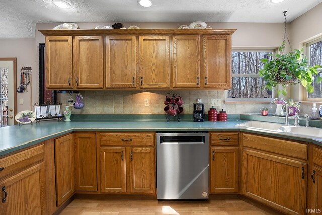 kitchen with brown cabinets, dishwasher, backsplash, and a sink