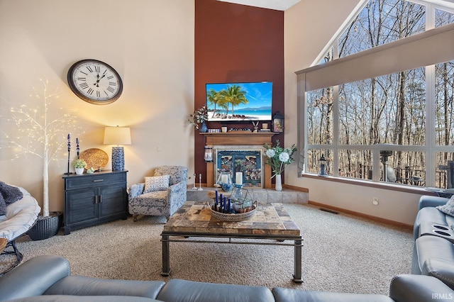 carpeted living area with a tile fireplace, a healthy amount of sunlight, visible vents, and a towering ceiling