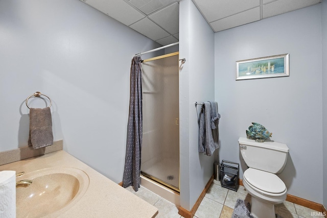 bathroom featuring a paneled ceiling, toilet, a stall shower, a sink, and tile patterned floors