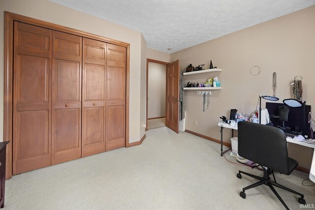 office area featuring baseboards, a textured ceiling, and light colored carpet