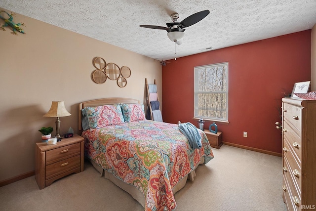 bedroom featuring a textured ceiling, light colored carpet, a ceiling fan, baseboards, and visible vents