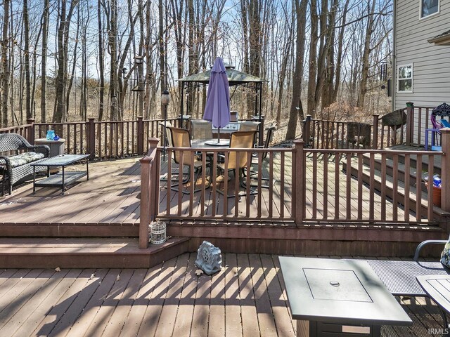 wooden deck with outdoor dining space and a gazebo