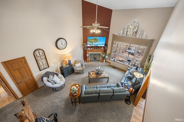 living room featuring high vaulted ceiling, a fireplace, ceiling fan, and wood finished floors