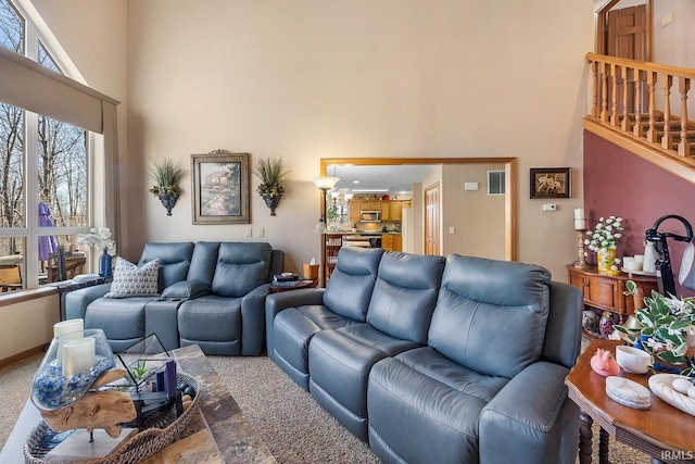 living area with visible vents, a towering ceiling, and baseboards