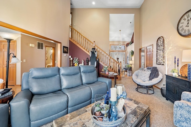 living area with stairs, carpet floors, a high ceiling, and visible vents