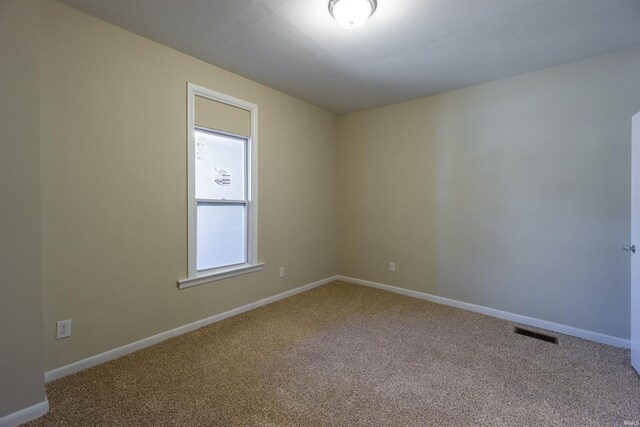 empty room featuring visible vents, baseboards, and carpet floors