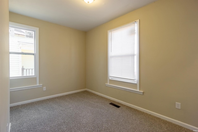 unfurnished room with carpet flooring, visible vents, and baseboards