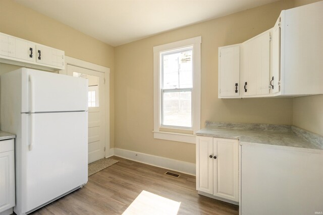 kitchen featuring visible vents, light wood-style floors, light countertops, and freestanding refrigerator