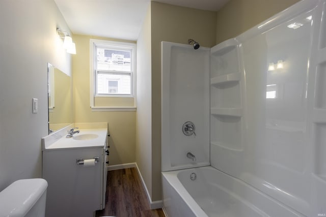 full bath featuring toilet, wood finished floors, vanity, baseboards, and shower / bathtub combination