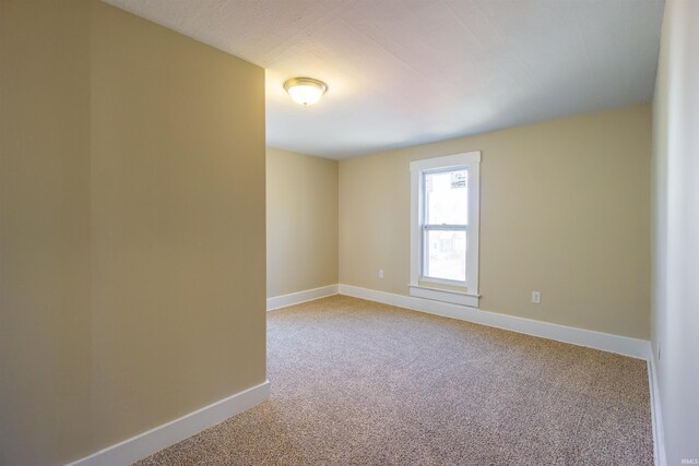 empty room featuring light colored carpet and baseboards