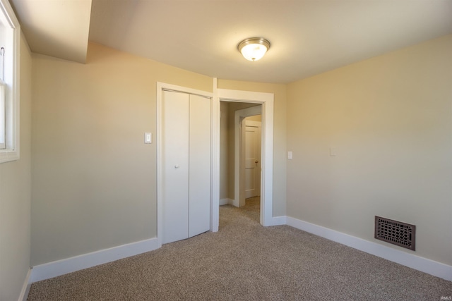 unfurnished bedroom with visible vents, baseboards, a closet, and carpet flooring